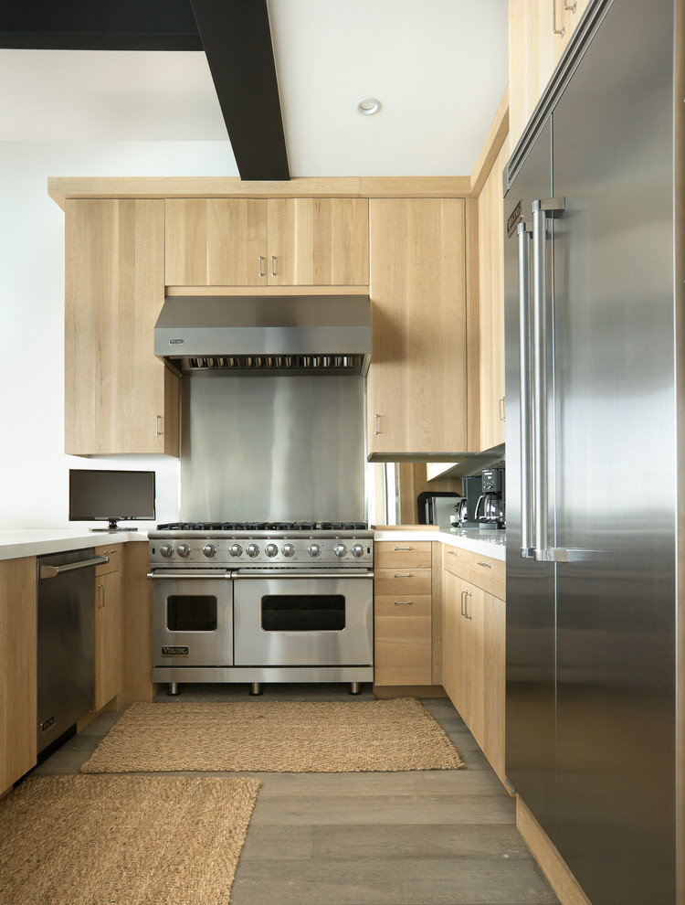 This is an example of a large contemporary u-shaped kitchen/diner in Los Angeles with flat-panel cabinets, light wood cabinets, metallic splashback, stainless steel appliances and light hardwood flooring.