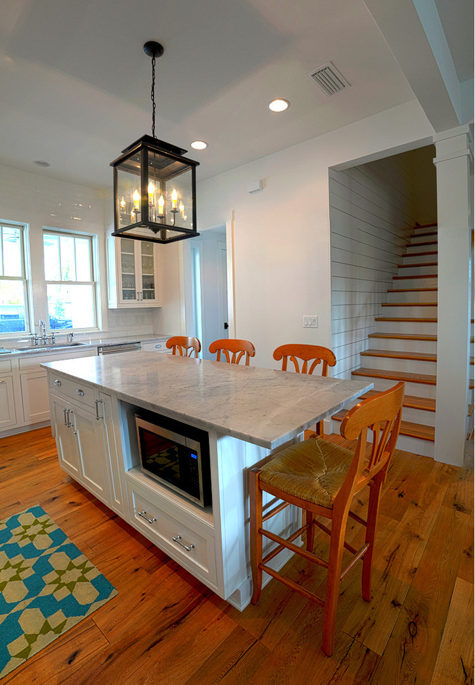 Example of a large beach style l-shaped marble floor eat-in kitchen design in Jacksonville with an undermount sink, shaker cabinets, white cabinets, marble countertops, white backsplash, subway tile backsplash, stainless steel appliances and an island