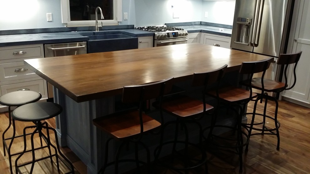 Inspiration for a large coastal l-shaped kitchen/diner in New York with a belfast sink, flat-panel cabinets, blue cabinets, wood worktops, stainless steel appliances, medium hardwood flooring and an island.