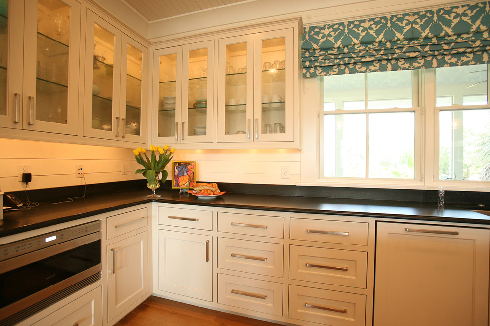Exempel på ett mellanstort exotiskt kök, med en undermonterad diskho, skåp i shakerstil, vita skåp, granitbänkskiva, vitt stänkskydd, stänkskydd i tunnelbanekakel, rostfria vitvaror och mellanmörkt trägolv