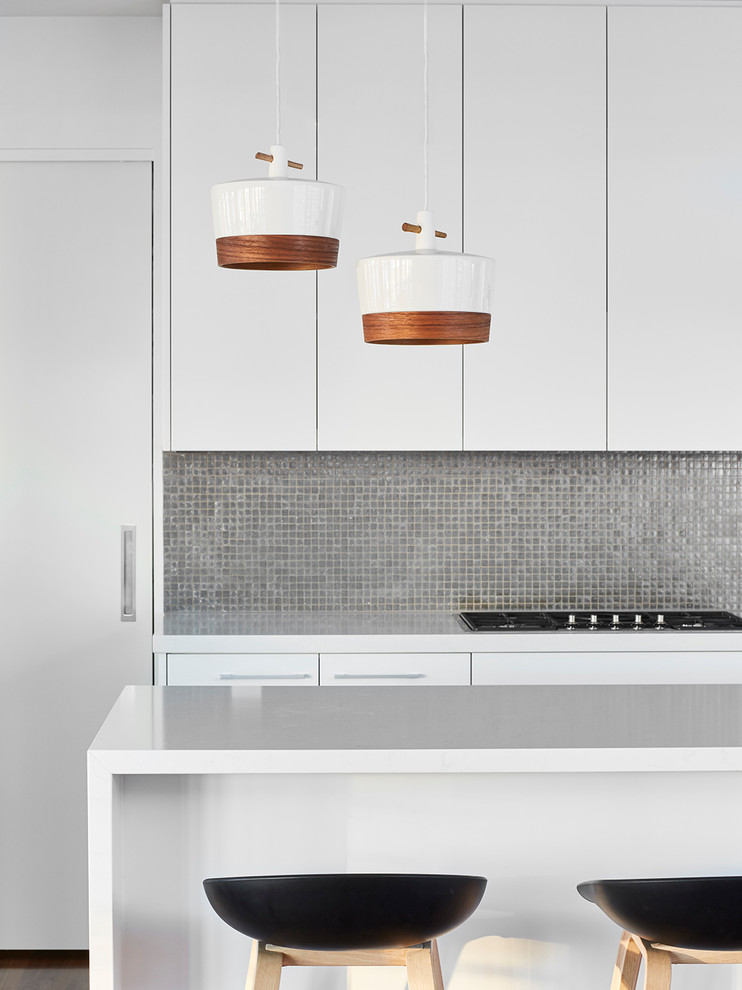 Moderne Küche mit flächenbündigen Schrankfronten, weißen Schränken, Küchenrückwand in Grau und Rückwand aus Mosaikfliesen in Sonstige