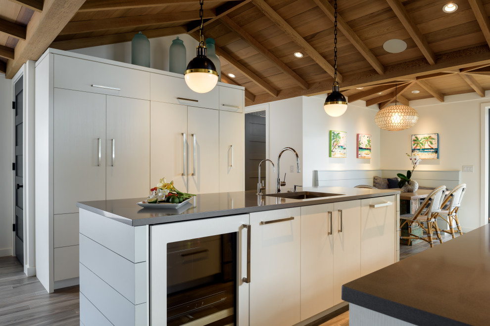 Idéer för ett mellanstort maritimt grå kök, med en undermonterad diskho, släta luckor, vita skåp, bänkskiva i kvarts, blått stänkskydd, stänkskydd i glaskakel, integrerade vitvaror, klinkergolv i porslin, en köksö och grått golv