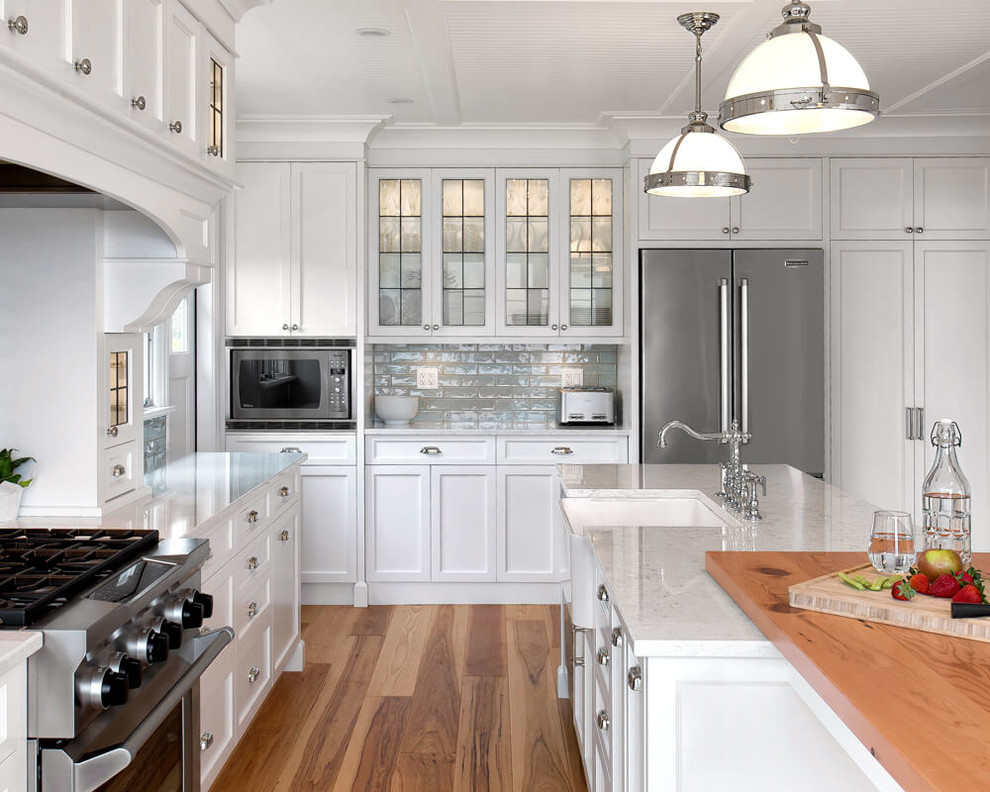 Große Klassische Küche mit Landhausspüle, Schrankfronten im Shaker-Stil, weißen Schränken, Küchenrückwand in Grau, Küchengeräten aus Edelstahl, hellem Holzboden und Kücheninsel in Vancouver