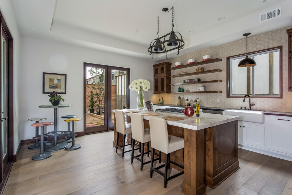 Eat-in kitchen - large transitional l-shaped light wood floor eat-in kitchen idea in Los Angeles with a farmhouse sink, shaker cabinets, dark wood cabinets, marble countertops, gray backsplash, stainless steel appliances and an island