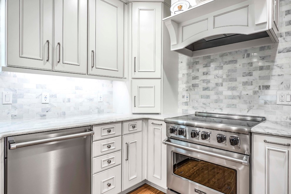 Design ideas for a medium sized classic galley kitchen/diner in Tampa with a submerged sink, recessed-panel cabinets, white cabinets, engineered stone countertops, white splashback, marble splashback, stainless steel appliances, light hardwood flooring, no island, brown floors and white worktops.
