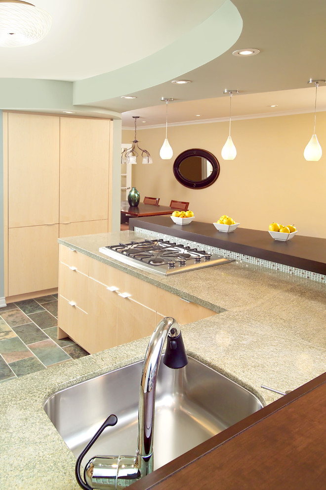 トロントにあるエクレクティックスタイルのおしゃれなキッチン (シングルシンク、フラットパネル扉のキャビネット、淡色木目調キャビネット、御影石カウンター、ガラスタイルのキッチンパネル、シルバーの調理設備、スレートの床、緑のキッチンパネル) の写真