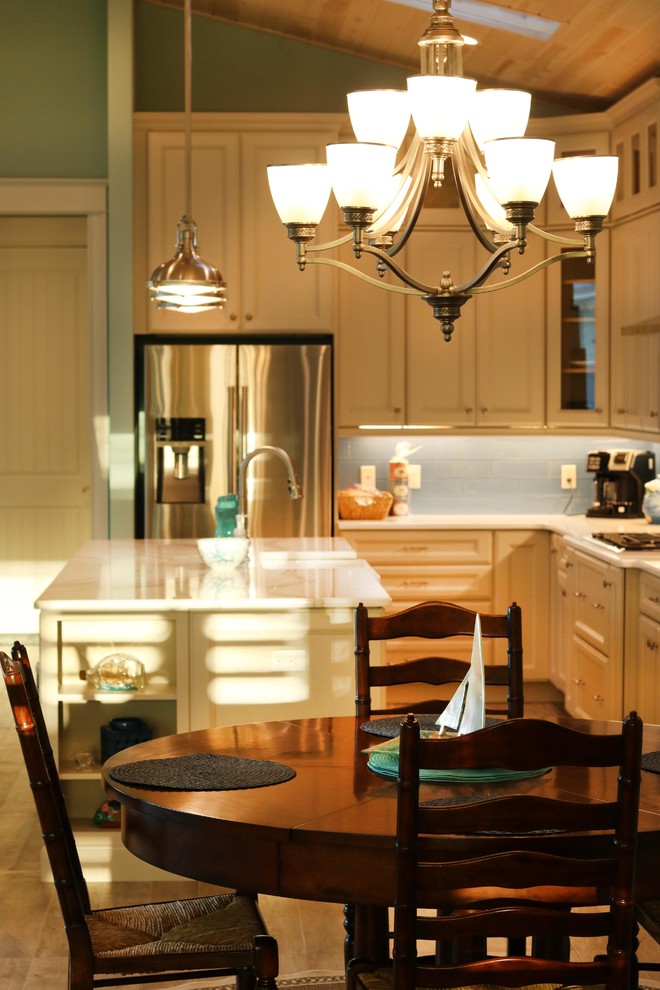 Foto på ett litet maritimt kök, med luckor med infälld panel, vita skåp, en köksö, en rustik diskho, bänkskiva i kvartsit, blått stänkskydd, stänkskydd i glaskakel och rostfria vitvaror