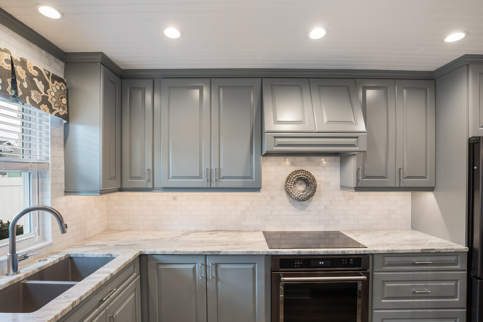 Foto på ett litet amerikanskt flerfärgad kök, med en undermonterad diskho, luckor med upphöjd panel, grå skåp, granitbänkskiva, vitt stänkskydd, stänkskydd i marmor, svarta vitvaror, vinylgolv, en köksö och brunt golv