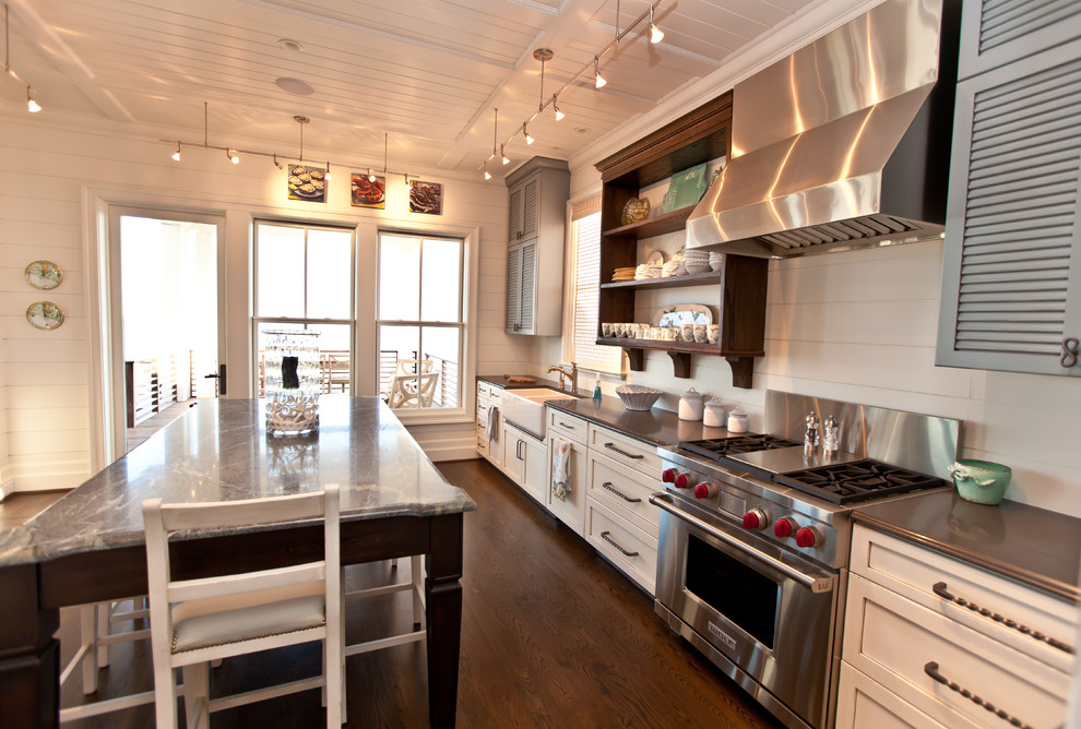 Diseño de cocina costera con electrodomésticos de acero inoxidable, encimera de esteatita, fregadero sobremueble, armarios con puertas mallorquinas y puertas de armario grises