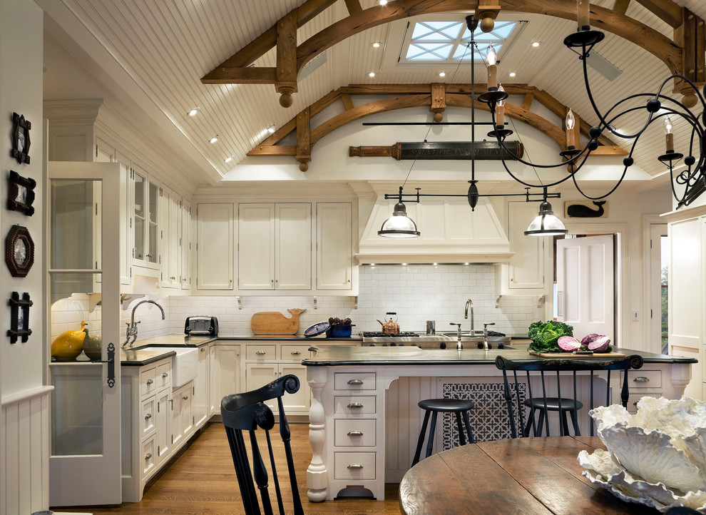 Inspiration for a large coastal l-shaped medium tone wood floor eat-in kitchen remodel in Boston with a single-bowl sink, recessed-panel cabinets, white cabinets, white backsplash, subway tile backsplash, stainless steel appliances and an island