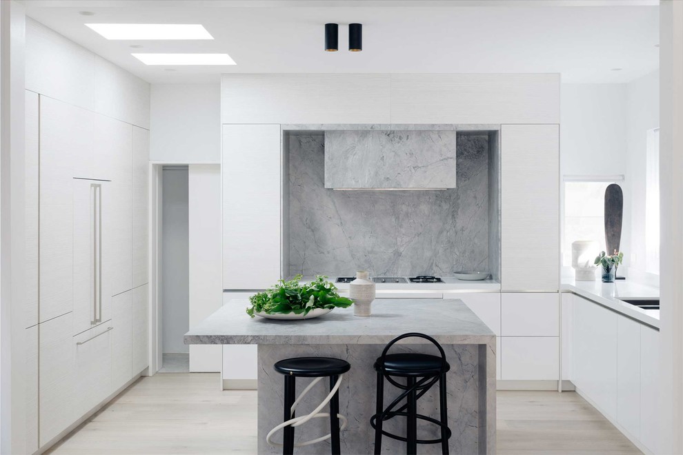 Foto på ett avskilt maritimt grå kök, med en dubbel diskho, släta luckor, vita skåp, grått stänkskydd, stänkskydd i sten, integrerade vitvaror, ljust trägolv, en köksö och beiget golv