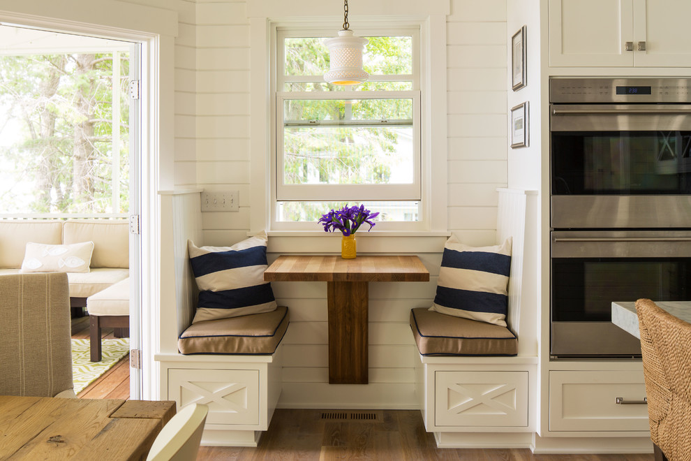 Imagen de cocina costera con armarios estilo shaker, puertas de armario blancas, electrodomésticos de acero inoxidable y suelo de madera oscura