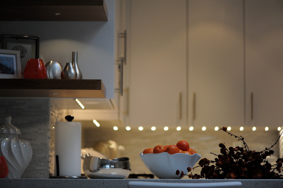 Idéer för ett mellanstort modernt vit kök, med en dubbel diskho, släta luckor, vita skåp, granitbänkskiva, grått stänkskydd, stänkskydd i stickkakel, integrerade vitvaror och en halv köksö