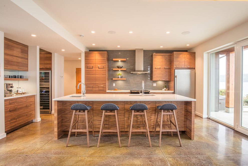 Example of a large trendy l-shaped concrete floor and brown floor eat-in kitchen design in Vancouver with an undermount sink, flat-panel cabinets, medium tone wood cabinets, quartzite countertops, gray backsplash, stone tile backsplash, stainless steel appliances, an island and white countertops