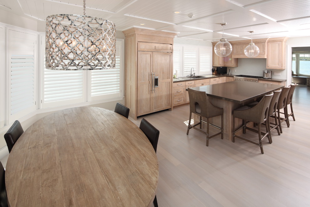 Beach style l-shaped light wood floor eat-in kitchen photo in Boston with recessed-panel cabinets, light wood cabinets, white backsplash, paneled appliances and an island