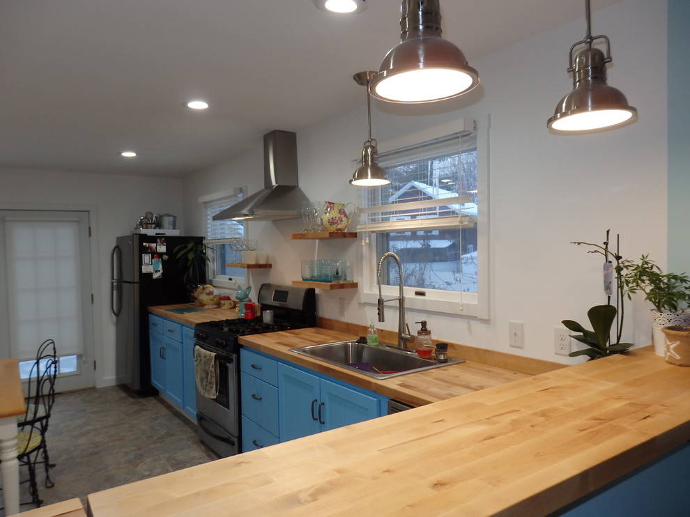 Lantlig inredning av ett stort brun linjärt brunt kök och matrum, med en nedsänkt diskho, skåp i shakerstil, blå skåp, träbänkskiva, rostfria vitvaror, klinkergolv i keramik och flerfärgat golv