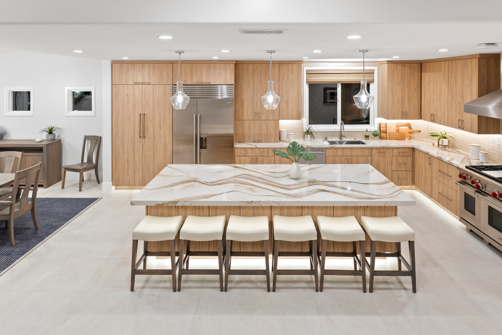 Eat-in kitchen - huge l-shaped porcelain tile and gray floor eat-in kitchen idea in San Diego with a single-bowl sink, flat-panel cabinets, light wood cabinets, quartz countertops, beige backsplash, glass tile backsplash, stainless steel appliances, an island and beige countertops