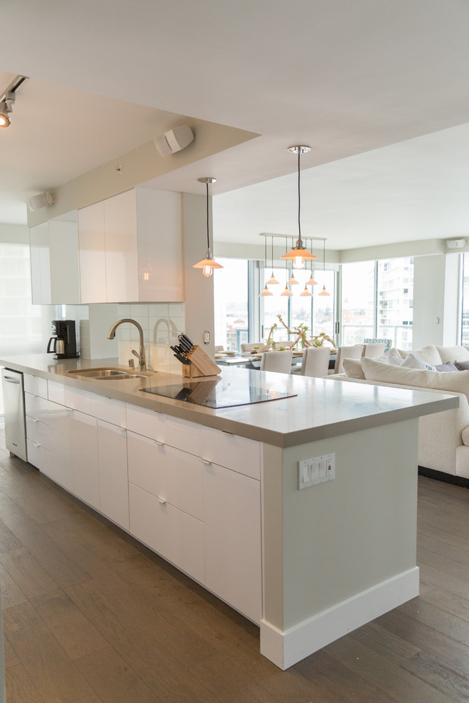 Large minimalist l-shaped light wood floor and brown floor open concept kitchen photo in San Diego with an undermount sink, flat-panel cabinets, white cabinets, quartz countertops, white backsplash, stainless steel appliances, no island and glass tile backsplash