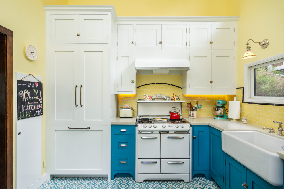 Inspiration for a small farmhouse u-shaped kitchen/diner in Los Angeles with a belfast sink, beaded cabinets, blue cabinets, engineered stone countertops, yellow splashback, metro tiled splashback, white appliances, cement flooring, blue floors and white worktops.