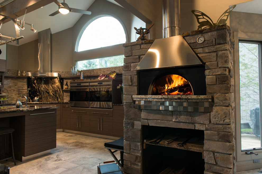 Cette image montre une cuisine américaine design en bois foncé et U de taille moyenne avec un sol en travertin, un évier encastré, un plan de travail en granite, une crédence beige, une crédence en carreau briquette, un électroménager en acier inoxydable, un placard à porte plane, îlot et un sol beige.