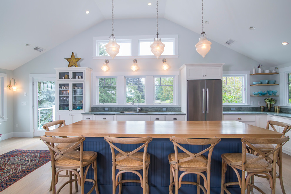 Foto di una cucina stile marinaro con lavello sottopiano, ante in stile shaker, ante blu, top in legno, elettrodomestici in acciaio inossidabile, parquet chiaro e pavimento beige