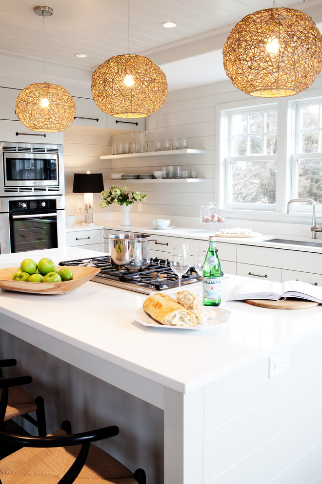 Kitchen - coastal u-shaped kitchen idea in Boston with flat-panel cabinets, white cabinets, white backsplash, wood backsplash, stainless steel appliances, an island and white countertops