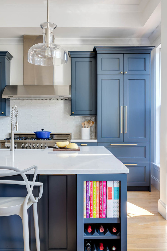 Foto de cocina comedor tradicional renovada con puertas de armario azules, electrodomésticos de acero inoxidable, suelo de madera clara, una isla y encimeras blancas