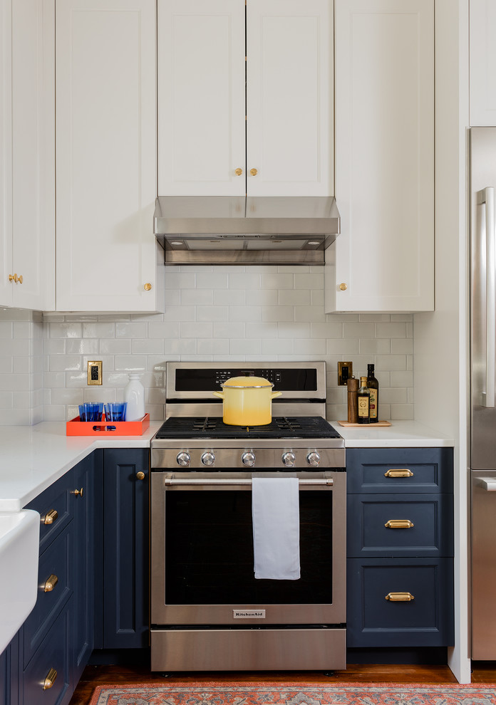 На фото: угловая кухня в классическом стиле с фасадами с утопленной филенкой, синими фасадами, белым фартуком, фартуком из плитки кабанчик и техникой из нержавеющей стали с