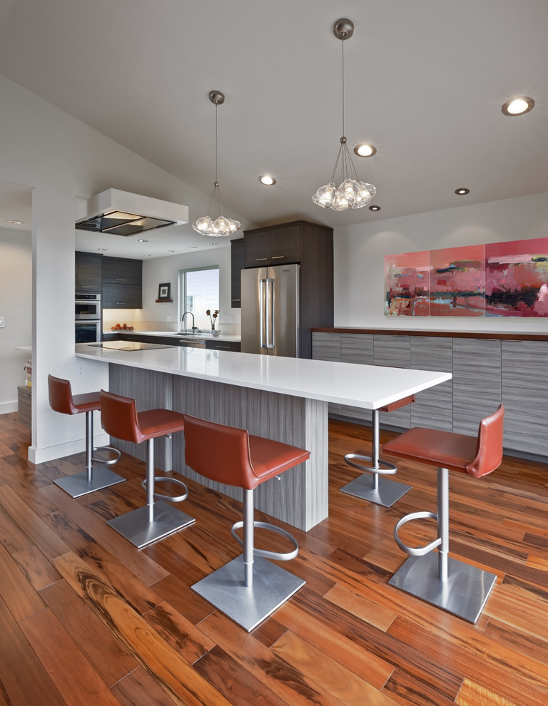 Example of a trendy medium tone wood floor open concept kitchen design in Seattle with an undermount sink, flat-panel cabinets, dark wood cabinets, quartz countertops, white backsplash, ceramic backsplash and stainless steel appliances