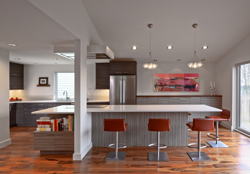 Exempel på ett modernt kök med öppen planlösning, med en undermonterad diskho, släta luckor, skåp i mörkt trä, bänkskiva i kvarts, vitt stänkskydd, stänkskydd i keramik, rostfria vitvaror och mellanmörkt trägolv