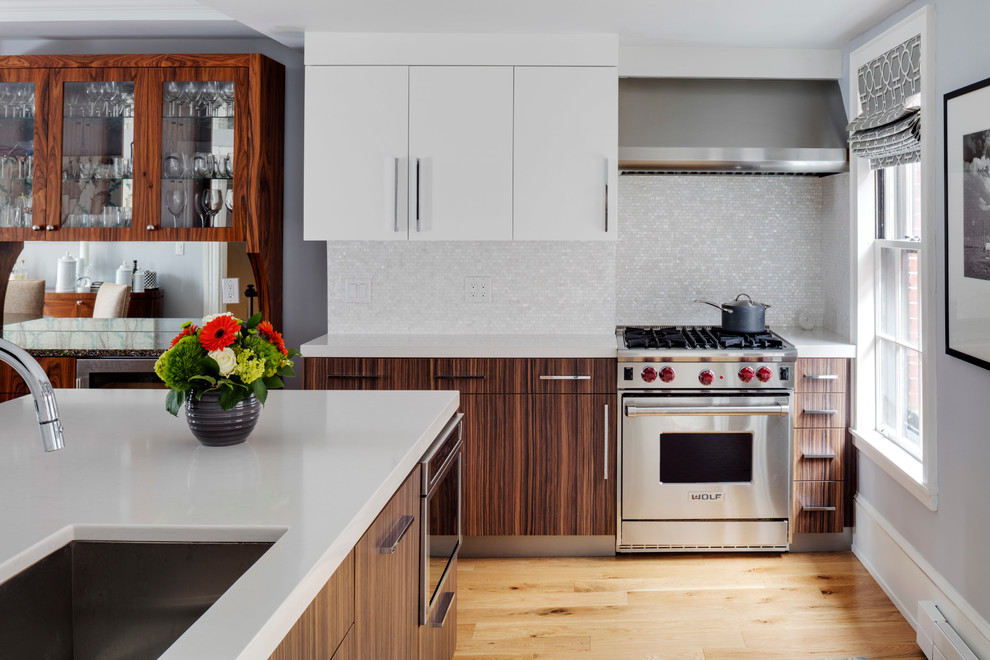 Moderne Küche mit Unterbauwaschbecken, flächenbündigen Schrankfronten, weißen Schränken, Küchenrückwand in Weiß, Küchengeräten aus Edelstahl, braunem Holzboden und Kücheninsel in Boston