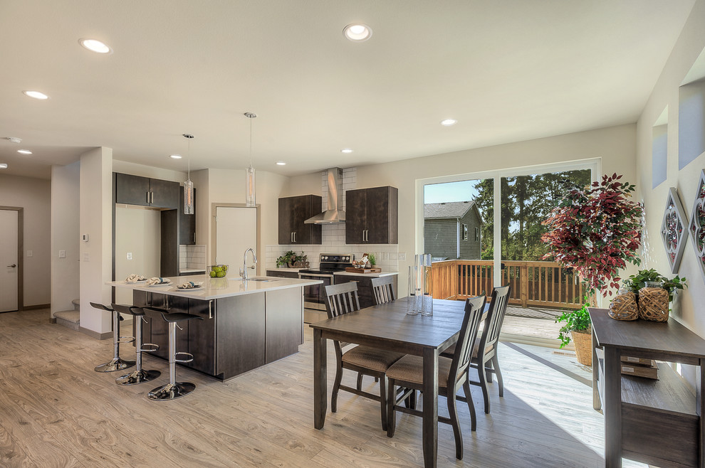 Large trendy single-wall light wood floor and gray floor eat-in kitchen photo in Seattle with a double-bowl sink, flat-panel cabinets, brown cabinets, granite countertops, white backsplash, subway tile backsplash, stainless steel appliances and an island
