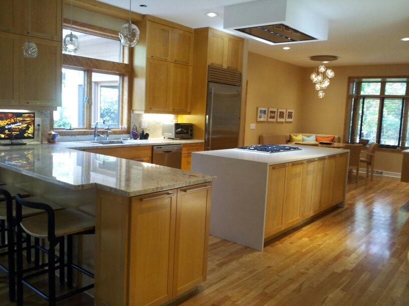 Bild på ett mellanstort funkis kök, med en undermonterad diskho, skåp i shakerstil, skåp i ljust trä, granitbänkskiva, beige stänkskydd, rostfria vitvaror, ljust trägolv och en köksö