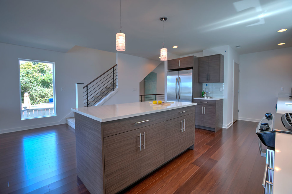 This is an example of a small contemporary galley kitchen/diner in Seattle with a submerged sink, flat-panel cabinets, engineered stone countertops, white splashback, metro tiled splashback, stainless steel appliances, bamboo flooring, an island, light wood cabinets and brown floors.