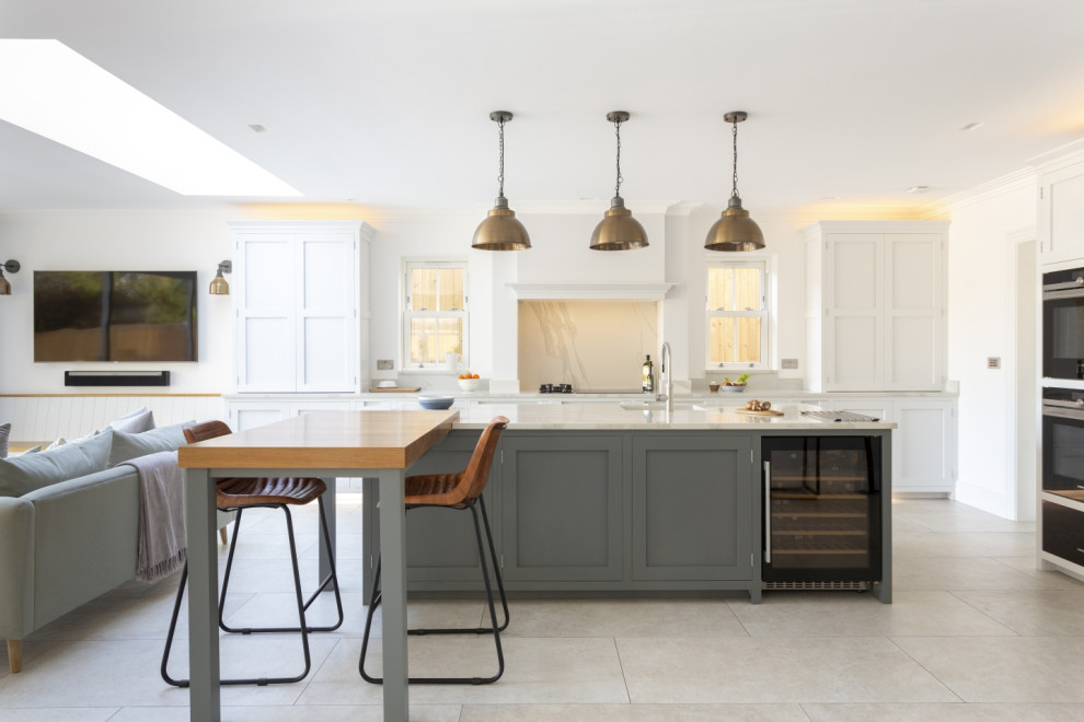 Photo of a large traditional open plan kitchen in Buckinghamshire with shaker cabinets, quartz worktops, white splashback, engineered quartz splashback, an island, grey floors and white worktops.