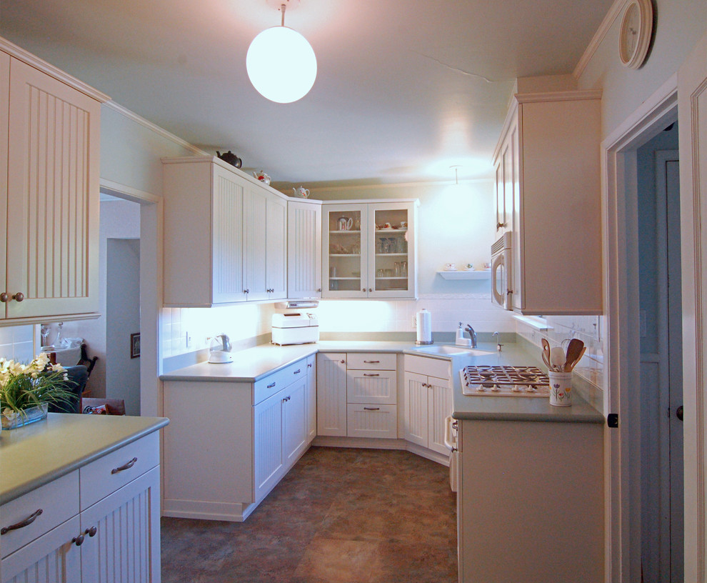 サンルイスオビスポにある小さなカントリー風のおしゃれなキッチン (一体型シンク、インセット扉のキャビネット、白いキャビネット、人工大理石カウンター、白いキッチンパネル、ガラスタイルのキッチンパネル、白い調理設備、リノリウムの床) の写真
