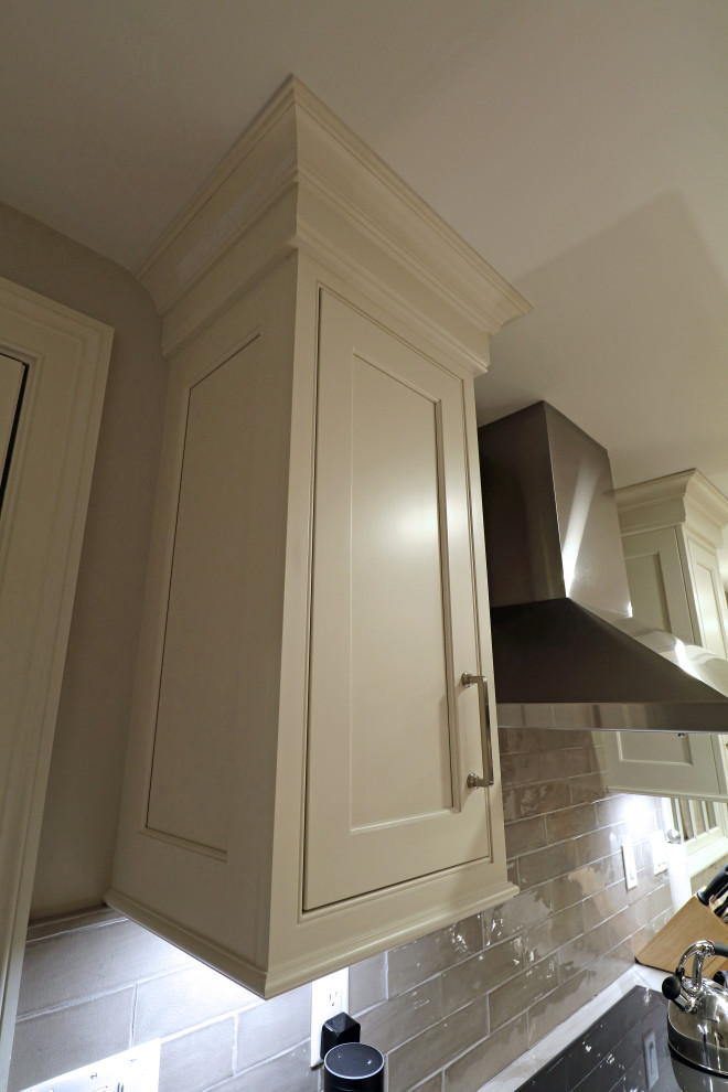 This is an example of a medium sized traditional single-wall kitchen/diner in Boston with a belfast sink, beaded cabinets, white cabinets, engineered stone countertops, grey splashback, ceramic splashback, stainless steel appliances, light hardwood flooring, an island, yellow floors and white worktops.