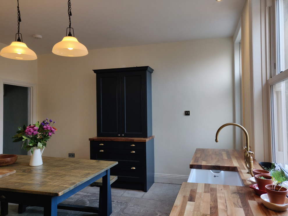 Idéer för att renovera ett mellanstort lantligt kök och matrum, med en rustik diskho, luckor med profilerade fronter, blå skåp, träbänkskiva, tegelgolv och en halv köksö