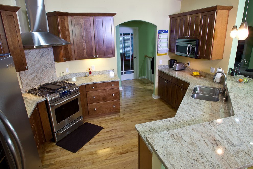 Example of a mid-sized transitional light wood floor eat-in kitchen design in Other with a double-bowl sink, shaker cabinets, medium tone wood cabinets, granite countertops, stainless steel appliances and a peninsula