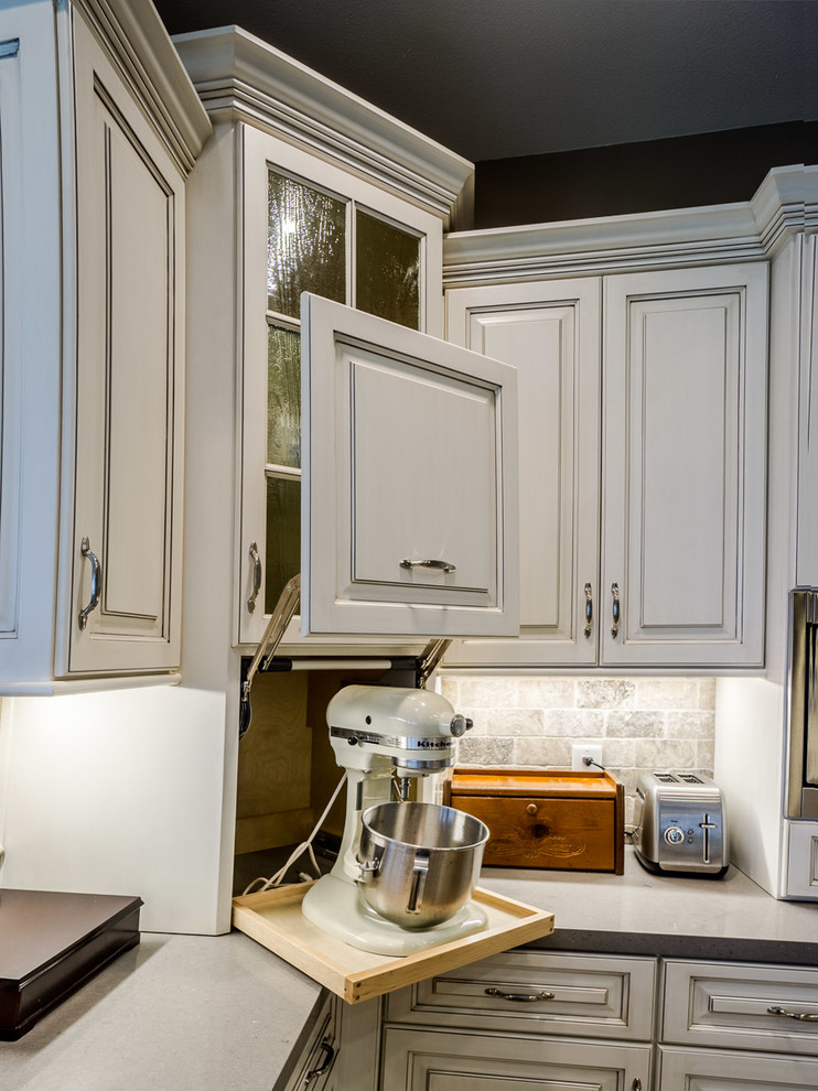 Klassisk inredning av ett stort kök, med en enkel diskho, luckor med upphöjd panel, vita skåp, bänkskiva i kvartsit, beige stänkskydd, stänkskydd i travertin, rostfria vitvaror, klinkergolv i porslin, en köksö och flerfärgat golv