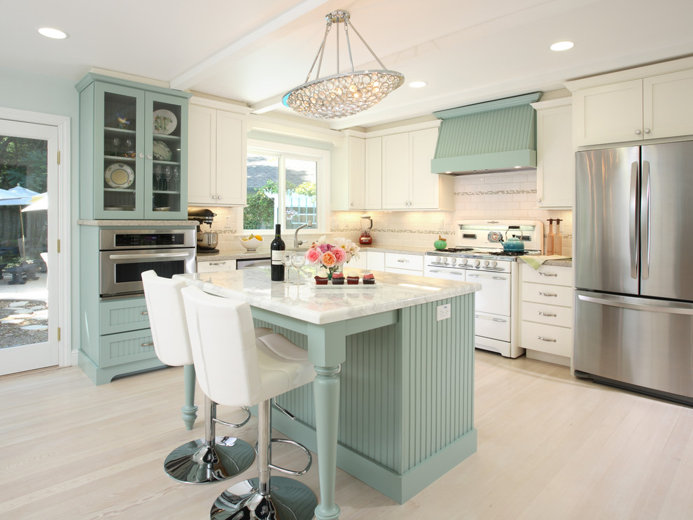 Inspiration for a large timeless l-shaped light wood floor eat-in kitchen remodel in San Francisco with a farmhouse sink, shaker cabinets, white cabinets, marble countertops, white backsplash, ceramic backsplash, stainless steel appliances and an island