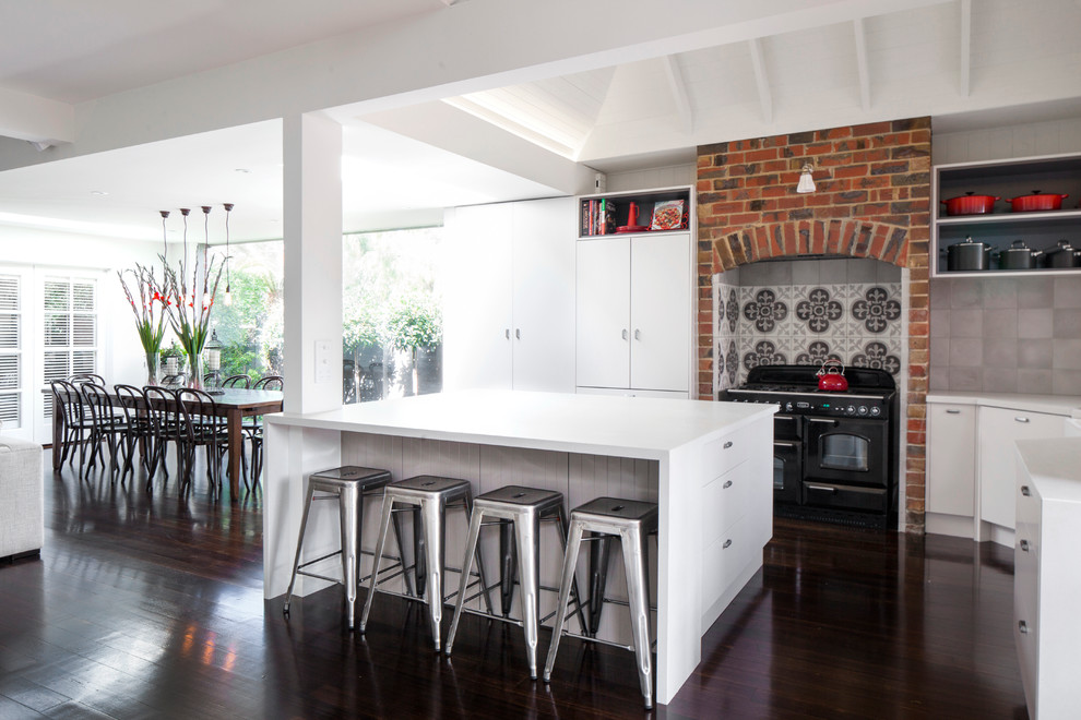 Große Moderne Wohnküche in L-Form mit dunklem Holzboden, Kücheninsel und schwarzen Elektrogeräten in Melbourne