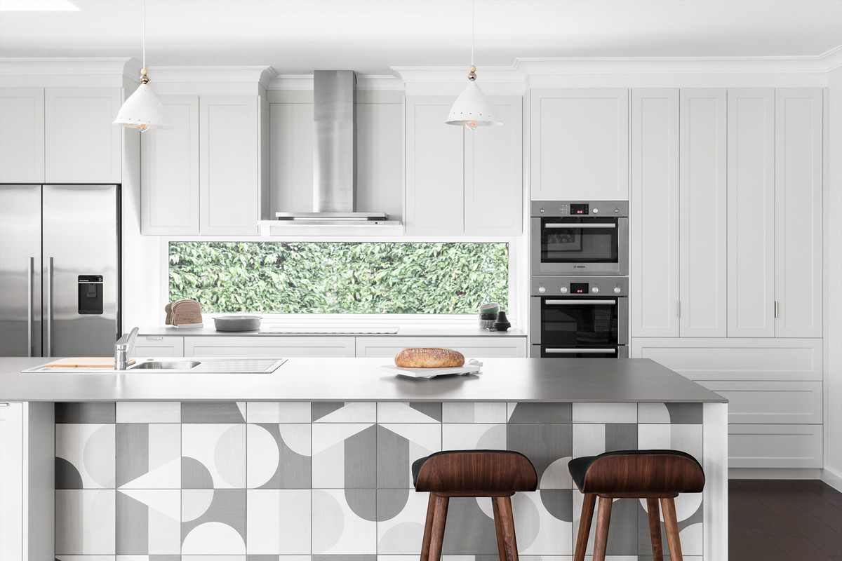 This is an example of a large scandinavian galley open plan kitchen in Melbourne with a submerged sink, shaker cabinets, white cabinets, engineered stone countertops, window splashback, stainless steel appliances, dark hardwood flooring, an island, brown floors and white worktops.