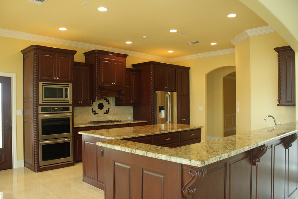 Example of a large classic galley porcelain tile eat-in kitchen design in Houston with an undermount sink, beaded inset cabinets, dark wood cabinets, granite countertops, beige backsplash, ceramic backsplash, stainless steel appliances and an island