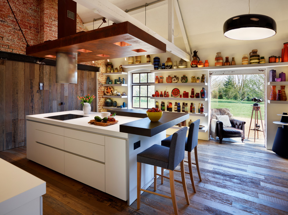 Inspiration for a medium sized contemporary single-wall kitchen/diner in Wiltshire with flat-panel cabinets, white cabinets, laminate countertops, white splashback, glass sheet splashback, stainless steel appliances, medium hardwood flooring and an island.