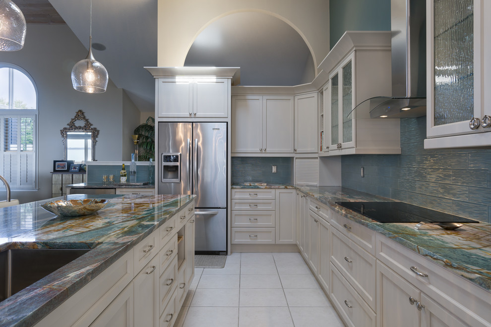 Exempel på ett mellanstort maritimt kök, med en undermonterad diskho, luckor med infälld panel, vita skåp, bänkskiva i onyx, blått stänkskydd, stänkskydd i glaskakel, rostfria vitvaror och en köksö