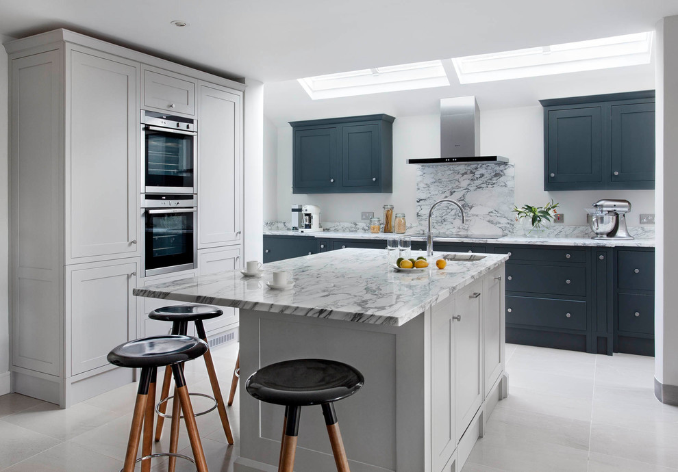 Bild på ett mellanstort funkis kök, med luckor med infälld panel, blå skåp, marmorbänkskiva, vitt stänkskydd, rostfria vitvaror och grått golv