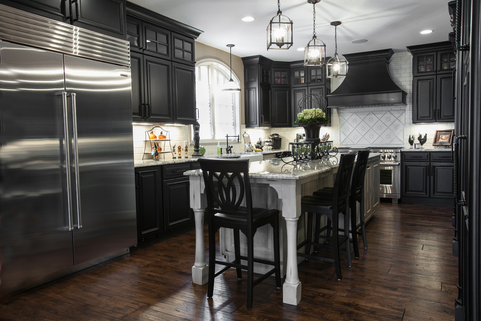 Example of a large classic u-shaped dark wood floor kitchen design in St Louis with a farmhouse sink, raised-panel cabinets, black cabinets, granite countertops, subway tile backsplash, stainless steel appliances and an island