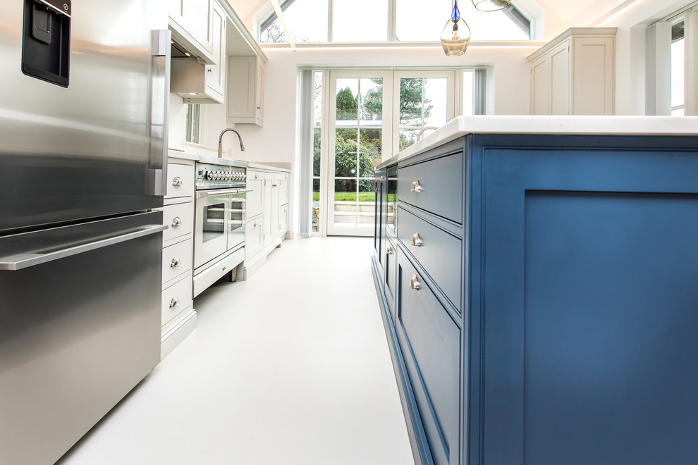 Inspiration for a large classic single-wall open plan kitchen in Hampshire with a double-bowl sink, shaker cabinets, blue cabinets, quartz worktops, white splashback, stone slab splashback, stainless steel appliances, ceramic flooring, an island, white floors and white worktops.