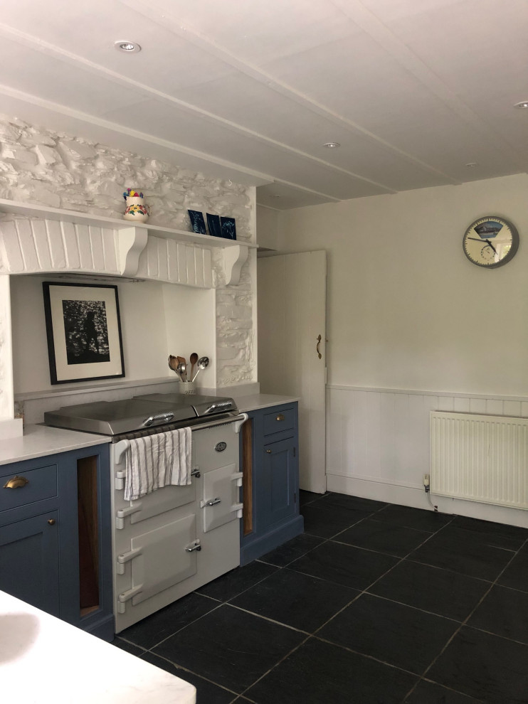 Inspiration for a medium sized farmhouse l-shaped enclosed kitchen in Surrey with flat-panel cabinets, blue cabinets, no island, black floors and white worktops.